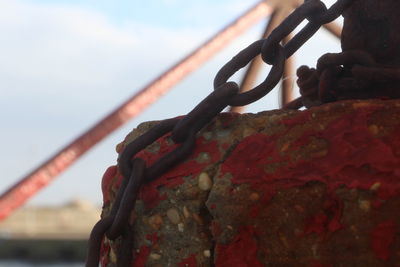 Close-up of rusty chain on bridge against sky