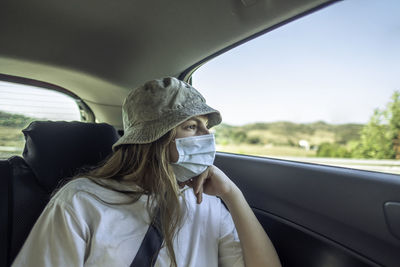 Close-up of girl wearing mask sitting in car