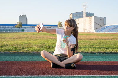 Active lifestyle. teen girl making selfie at the stadium after workout drinking water