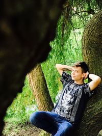 Young woman sitting on tree trunk in forest