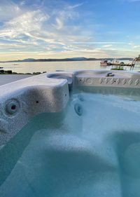 Close-up of swimming pool by sea against sky during sunset