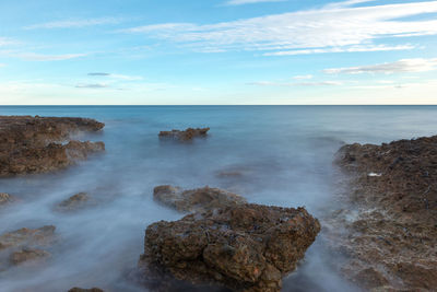 Scenic view of rocks in sea against sky