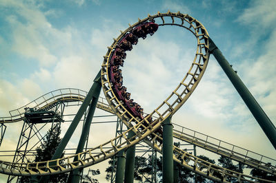 Low angle view of rollercoaster against cloudy sky