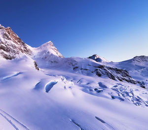 Scenic view of snowcapped mountains against clear blue sky