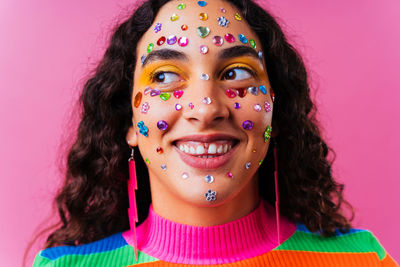 Close-up portrait of smiling young woman wearing mask against pink background