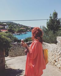 Rear view of woman holding umbrella against sea