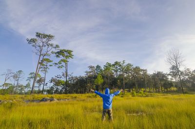 Rear view of man standing on field against sky