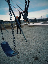 Low angle view of swing hanging on playground