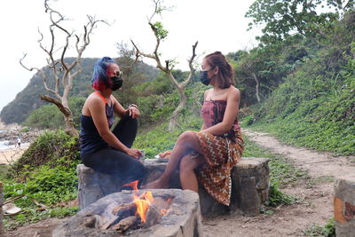 Young couple sitting on wood against trees