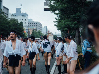 Rear view of people walking on street in city