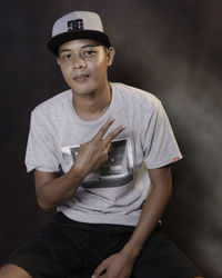 Portrait of young man standing against black background