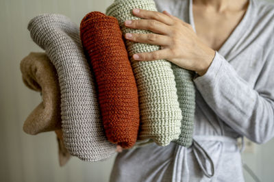 Woman holding clean folded sweaters at home