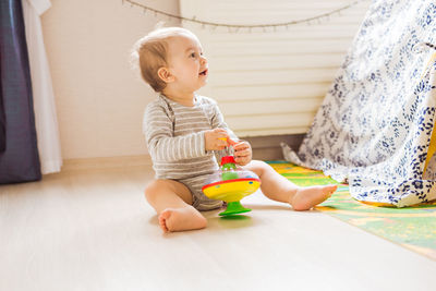Cute boy playing with toy sitting on floor