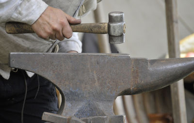 Midsection of man working on metal in workshop