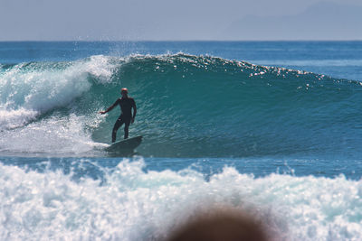 Man surfing in sea against sky