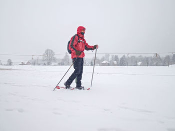 Man standing on snow covered field against sky