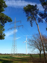 Low angle view of electricity pylon on field