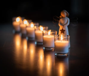 Close-up of illuminated candles with figurine on table