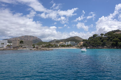 Scenic view of sea by townscape against sky