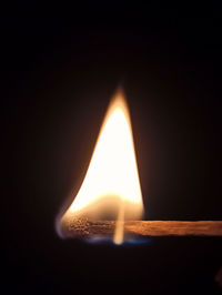 Close-up of lit candle in darkroom