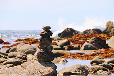 Stack of stones at beach against sky