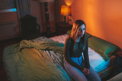 Woman sitting on bed at home