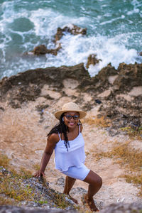 Full length of woman sitting on rock at beach