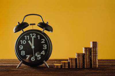 Close-up of clock on table against yellow background