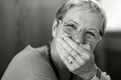 Portrait of woman wearing eyeglasses covering mouth