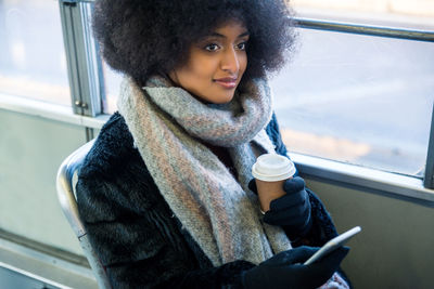 Young woman drinking coffee while sitting in car