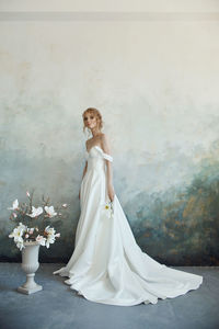 Full length portrait of bride standing by wall