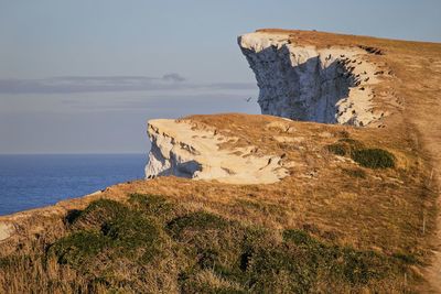 Rock formations by sea against sky