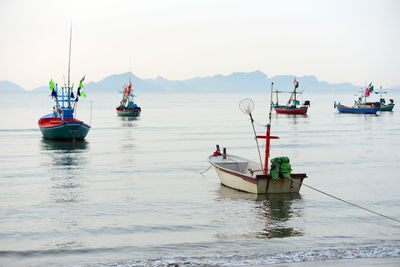 Fishing boats moored in sea against clear sky