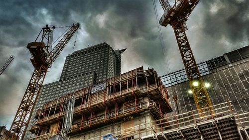 Low angle view of crane against cloudy sky