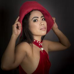 Portrait of young woman wearing hat against black background