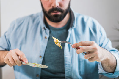 A plate of pancakes with cheese and avocado is on the table. an anonymous man is eating