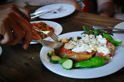 Cropped image of person eating salad on table at restaurant