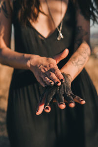 Midsection of woman holding hands standing outdoors