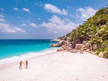 Rear view of couple standing at beach against sky