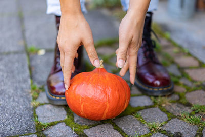 Midsection of person holding pumpkin on footpath