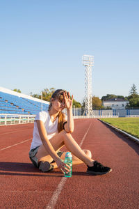 Full length of young woman sitting outdoors