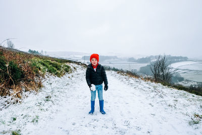 Full length of man standing on snow covered road