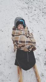 Portrait of smiling toddler on sledge in snow