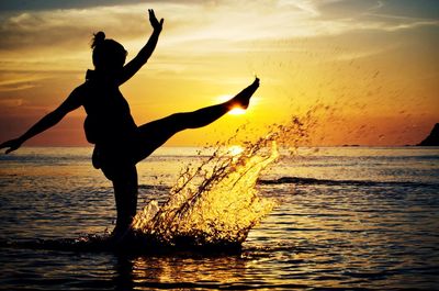 Silhouette woman in calm sea at sunset