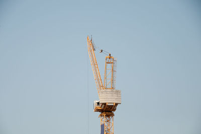 Low angle view of crane against clear sky