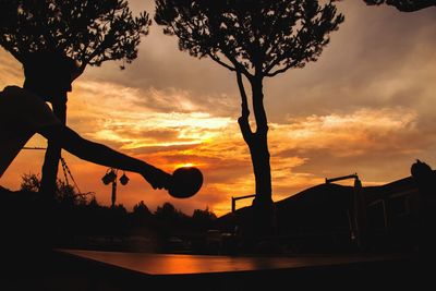 Silhouette trees by swimming pool against sky during sunset