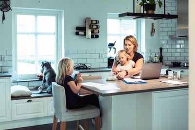 Mother with daughters sitting by table at home