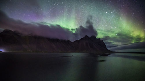 Scenic view of sea and mountains against sky at night