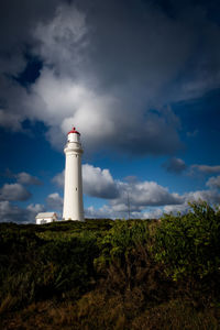 Low angle view of lighthouse by building against sky