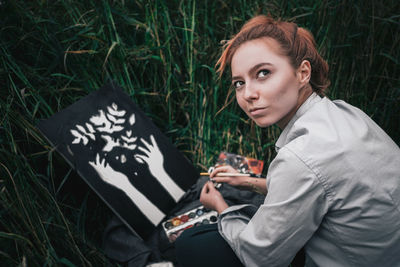 Portrait of young woman using mobile phone in grass